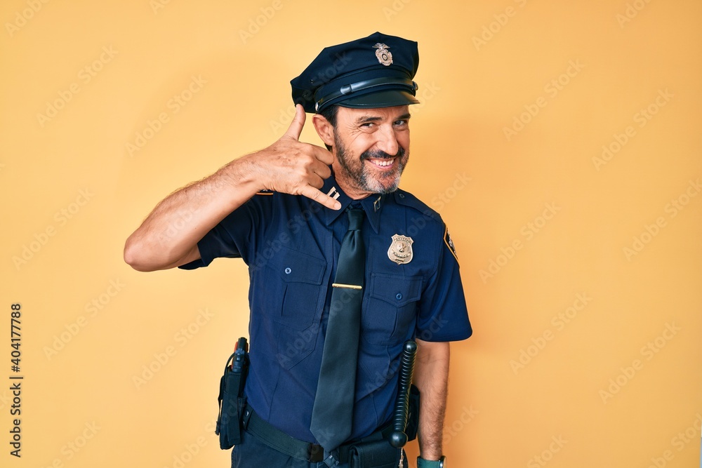Middle age hispanic man wearing police uniform smiling doing phone gesture with hand and fingers like talking on the telephone. communicating concepts. Middle age hispanic man wearing police uniform smiling doing phone gesture with hand and fingers like talking on the telephone. communicating concepts.