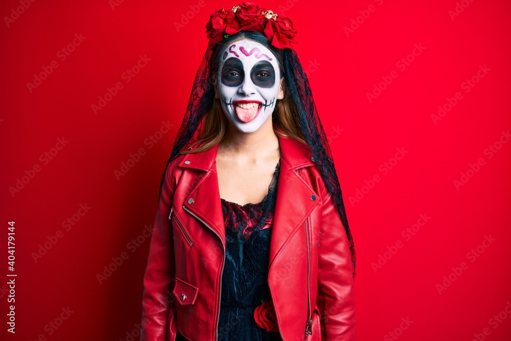 Woman wearing day of the dead costume over red sticking tongue out happy with funny expression. emotion concept. Woman wearing day of the dead costume over red sticking tongue out happy with funny expression. emotion concept.