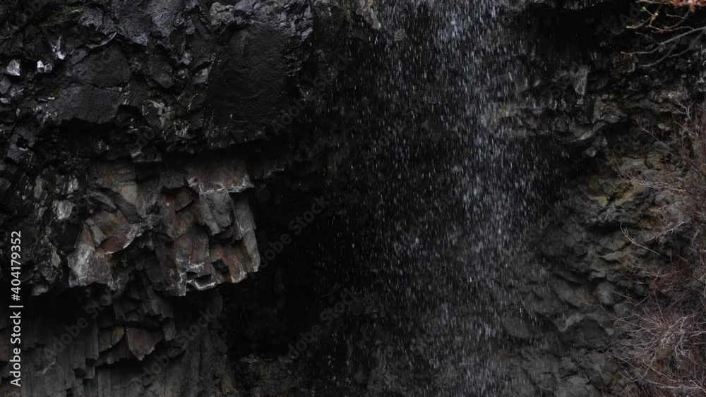Close up water shower trickling down a dark cliff. Close up water shower trickling down a dark cliff.