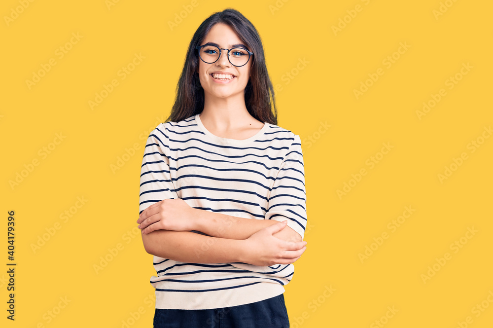 Brunette teenager girl wearing casual clothes and glasses happy face smiling with crossed arms looking at the camera. positive person. Brunette teenager girl wearing casual clothes and glasses happy face smiling with crossed arms looking at the camera. positive person.