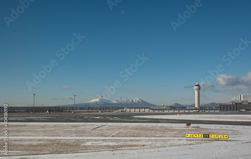 雪に覆われた恵庭岳と樽前山を背景にした新千歳空港の滑走路と管制塔