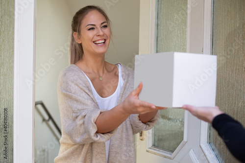 woman receiving package box from postman in front of house and happy surprised