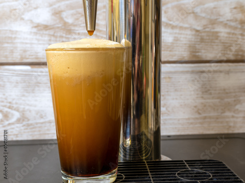 Nitro Cold Brew coffee in a clear glass with fine nitrogen bubbles and a smooth texture on a keg coffee dispenser.