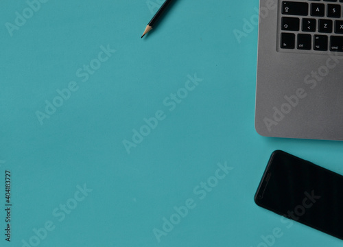 notebook, smartphone and pencil on a turquoise desk