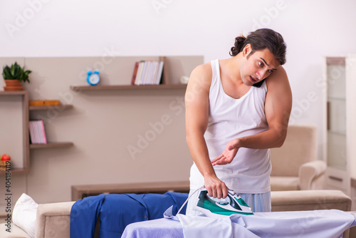 Young male employee ironing in the morning