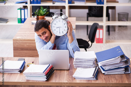 Young male employee unhappy with excessive work in time manageme photo