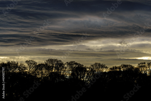 A dramatic stormy sky with clouds at sunset and a forest in Ireland
