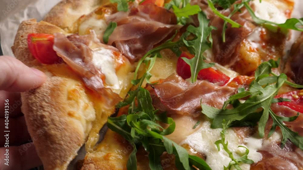 Prosciutto pizza with strachatella cheese, tomatoes and arugula leaves. Rotating on wooden table Prosciutto pizza with strachatella cheese, tomatoes and arugula leaves. Rotating on wooden table