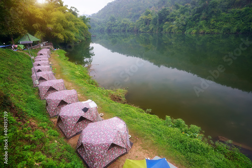 camping tent and cabin campsite on river khwae with water reflection and morning mist in green jungle at erawan waterfall national park for summer holiday relax and vacation travel trip on cool nature photo