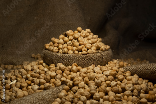 side view of chickpea in antique sack. Uncooked Dry chickpeas in sack isolated on burlap background. Grains are scattered out of the bag. Heap of legume chickpeas background with sackcloth