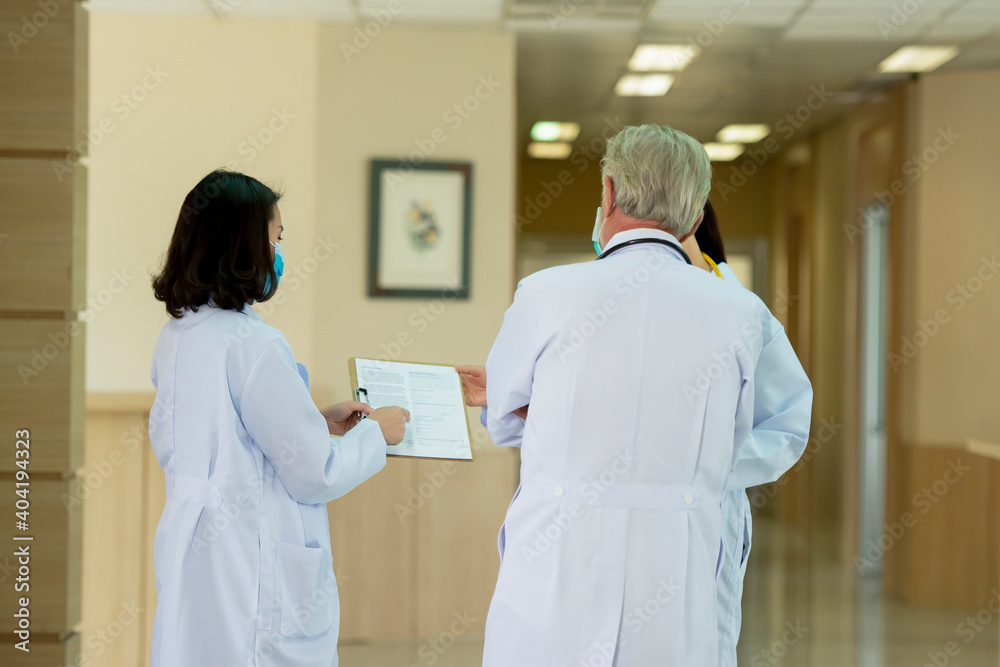 Obraz premium Doctors team wearing mask consult while walking at hospital