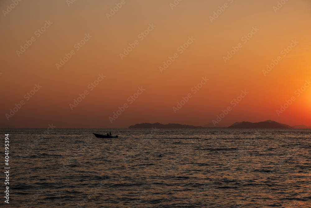 A boat glides across the waters of South China Sea during the sunset