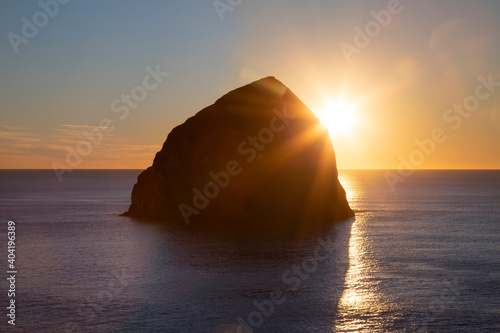 Haystack rock in silhouette  with partially clouded blue sky at sunset  along the Pacific ocean coastline  Oregon