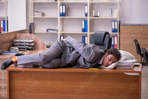 Young male employee sleeping at workplace