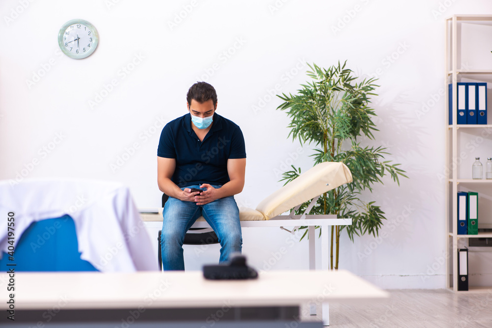 Young man waiting for doctor during pandemic in hospital