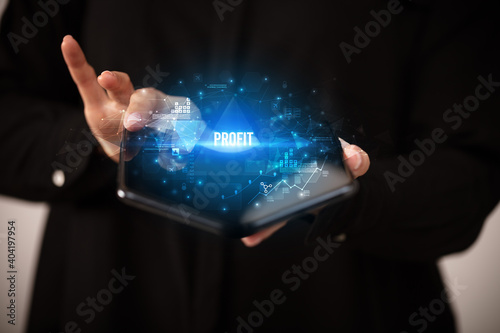 Businessman holding a foldable smartphone with PROFIT inscription, business concept