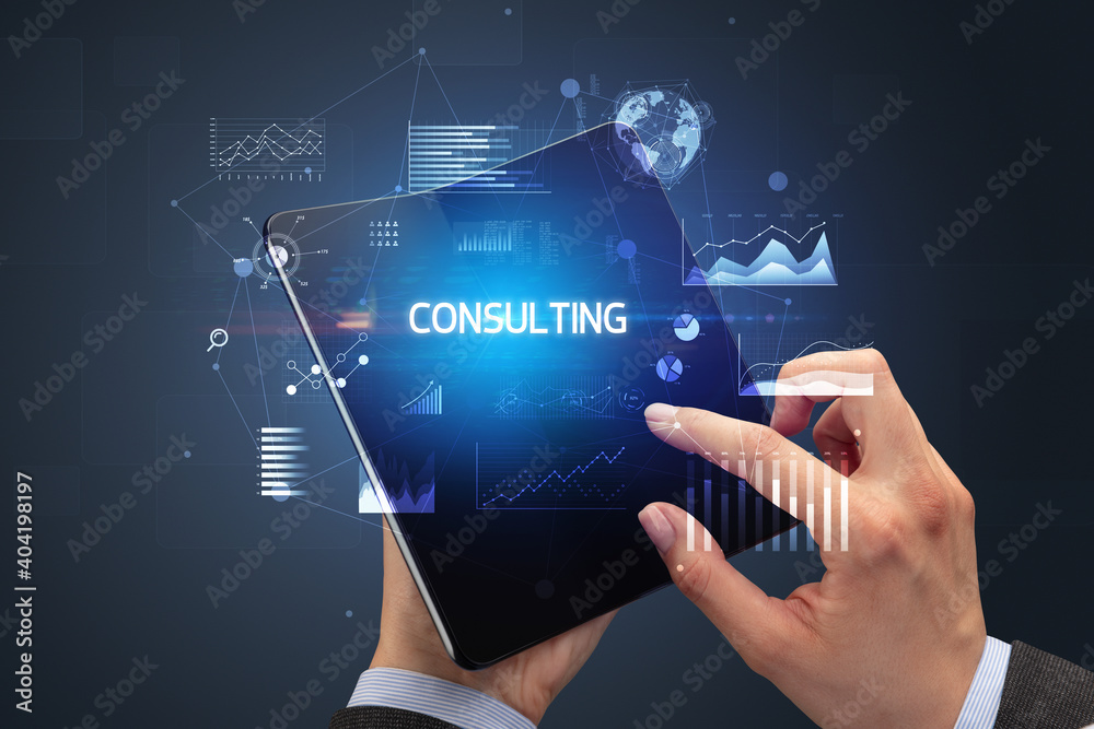 Businessman holding a foldable smartphone with CONSULTING inscription, successful business concept Businessman holding a foldable smartphone with CONSULTING inscription, successful business concept
