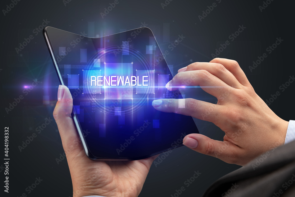 Businessman holding a foldable smartphone with RENEWABLE inscription, new technology concept Businessman holding a foldable smartphone with RENEWABLE inscription, new technology concept