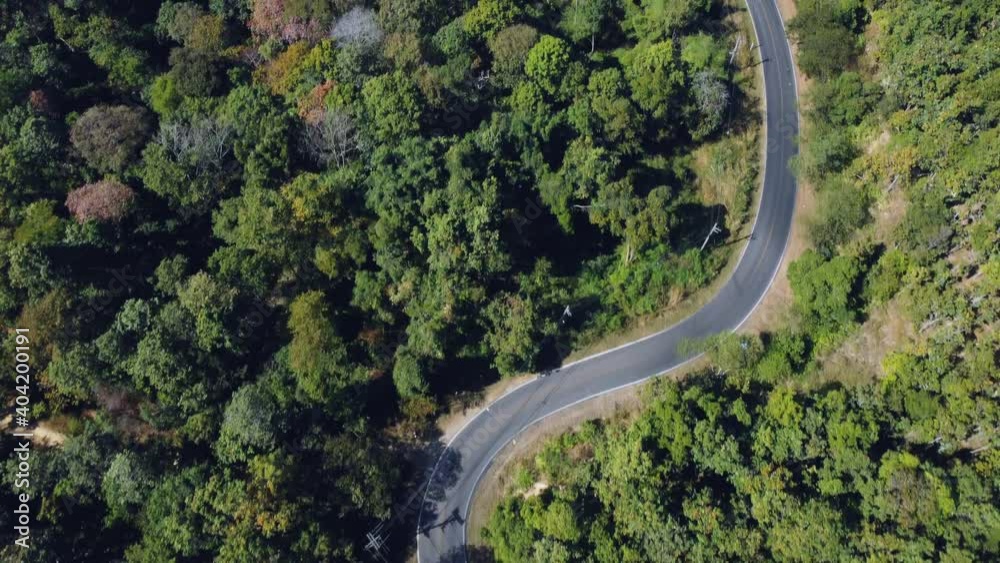 Establishing aerial top view shot of country side road passing through the green forest and mountain. Establishing aerial top view shot of country side road passing through the green forest and mountain.
