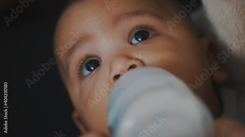Beautiful baby dringking his formula milk from the bottle in the hands of his mom. High quality 4k footage photo
