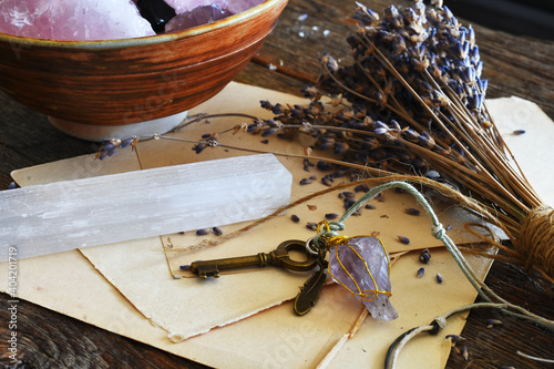 A close up image of old vintage writing paper, selenite wand, homemade pendulum, and dried lavender.  photo