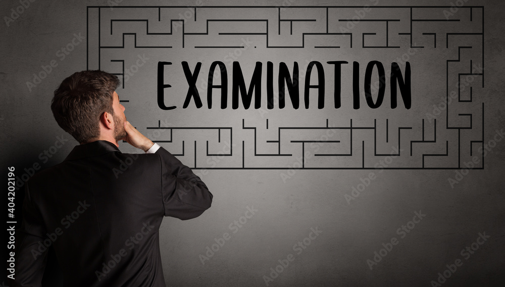 businessman drawing maze with EXAMINATION inscription, business education concept businessman drawing maze with EXAMINATION inscription, business education concept