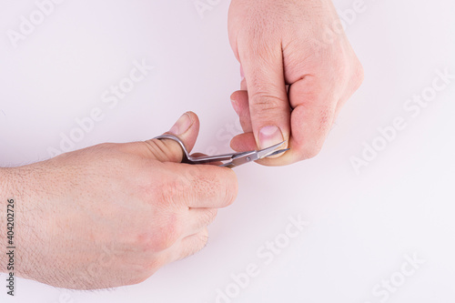 Men's hands cut their fingernails with scissors on a white background
