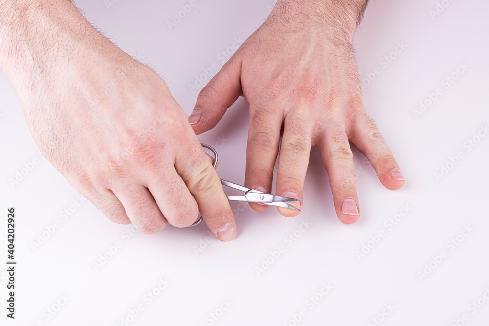 Men's hands cut their fingernails with scissors on a white background