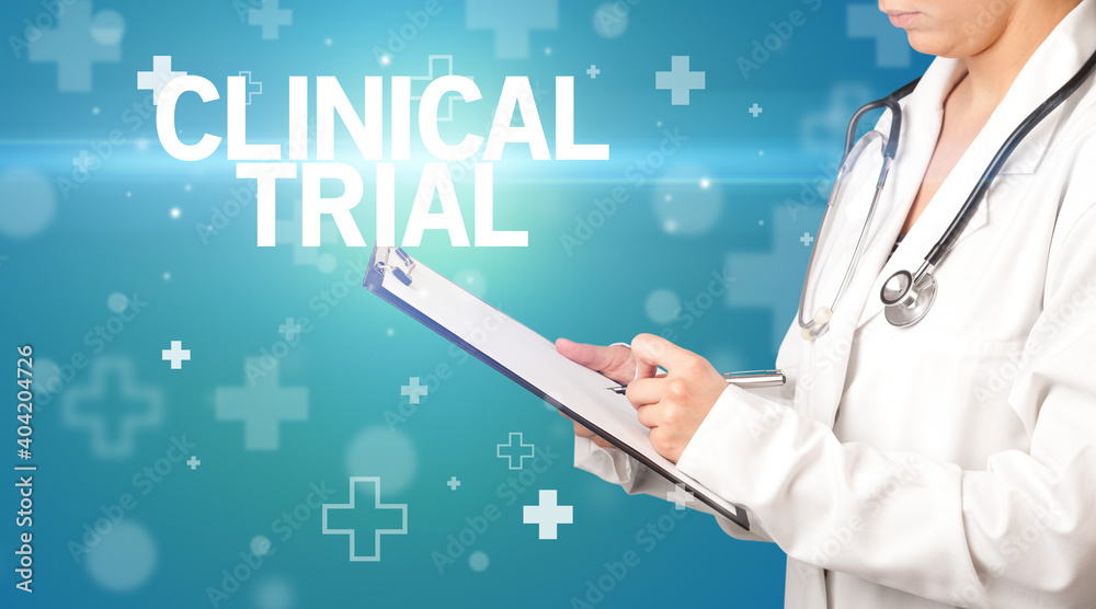 doctor writes notes on the clipboard with CLINICAL TRIAL inscription, first aid concept doctor writes notes on the clipboard with CLINICAL TRIAL inscription, first aid concept