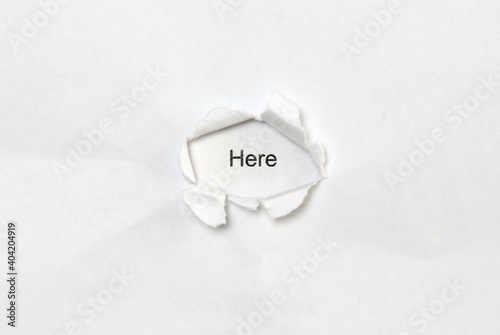 Word here on white isolated background, the inscription through the wound hole in paper. Concept of gender identity and sexual minorities. Stock photo for web and print with empty space for text