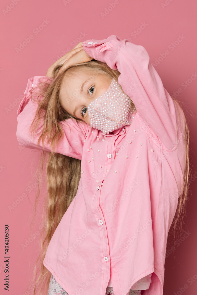 Little girl in pink clothes and a medical mask on a pink background Little girl in pink clothes and a medical mask on a pink background