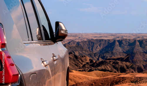 Close-up of a vehicle in the sand before a cliff. Moon valley. Africa.