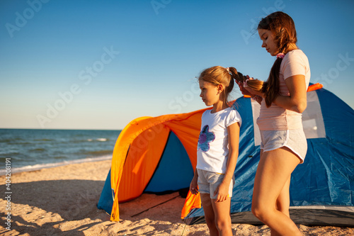Gentle care for loved ones and younger ones girls on the deserted coast of the warm beautiful sea on a beautiful evening