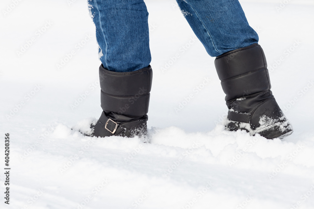 Male feet in black boots, winter walking in snow Male feet in black boots, winter walking in snow