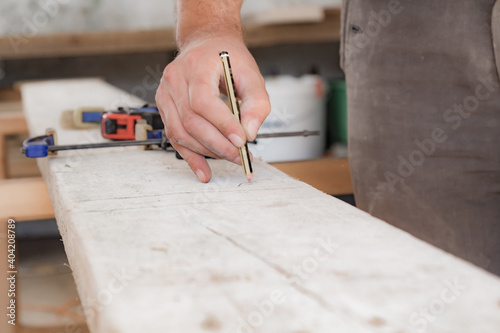 Male carpenter working with wood material in a garage.