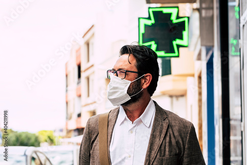 Adult man walking on the street wearing medical mask outdoor for coronavirus covid-19 healthy restrictions - people with protection disposable system mask in outbreak covid-19 virus photo