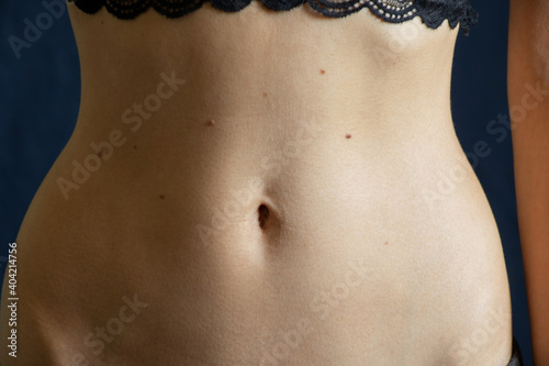 Fotografie navel and belly of a young girl closeup on a dark background