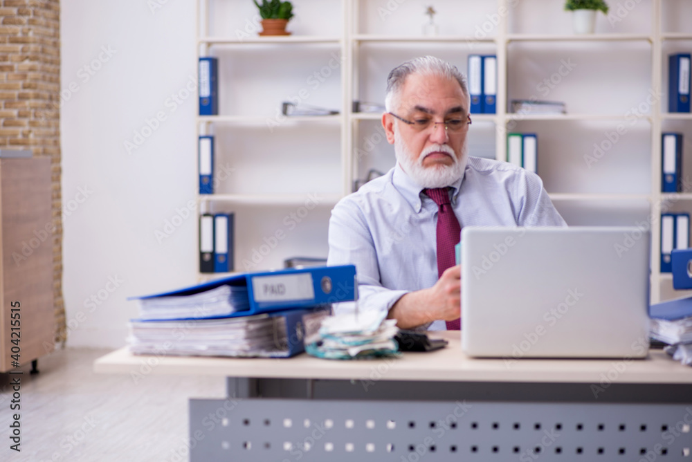Old male accountant in budget planning concept in the office Old male accountant in budget planning concept in the office