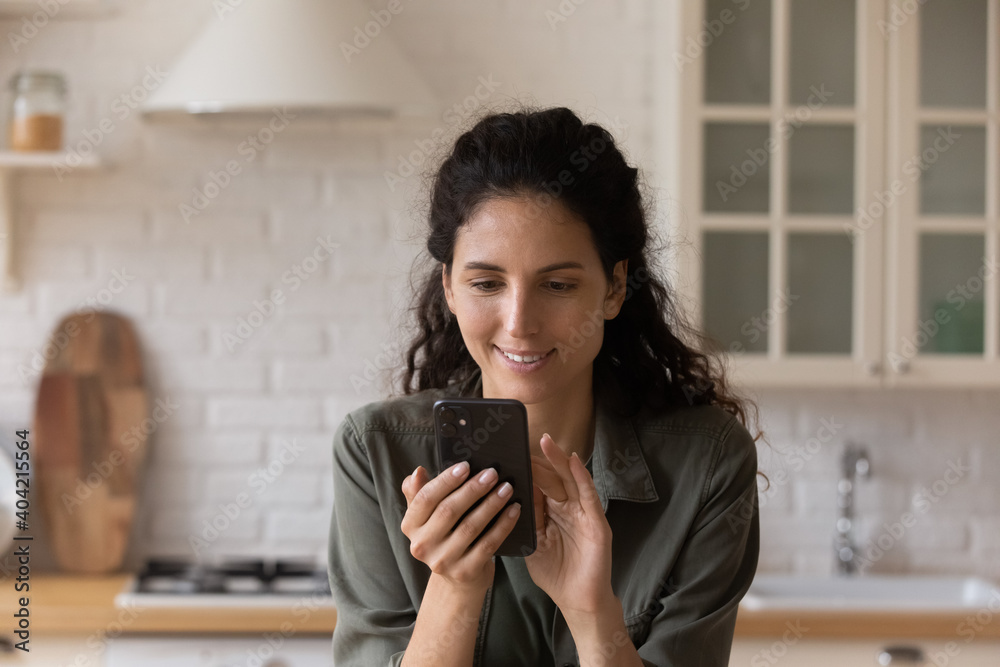 Happy young Caucasian woman look at cellphone screen shopping online on gadget from home. Smiling millennial female use smartphone browse good wireless internet on device. Technology concept. Happy young Caucasian woman look at cellphone screen shopping online on gadget from home. Smiling millennial female use smartphone browse good wireless internet on device. Technology concept.
