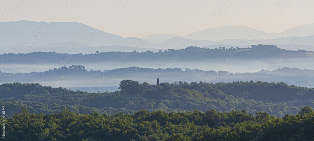 Scenic view of foggy dawn on the hills - Fogg is rising from vineyards and hiils in Chianciano, Tuscany on a misty early autumn morning