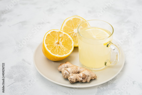 Cup of ginger and lemon lemonade with ingredients in plate