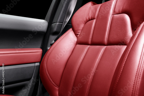 Modern luxury car red leather interior. Part of red leather car seat details with stitching. Interior of prestige car. Comfortable perforated leather seats. Perforated leather. © Aleksei