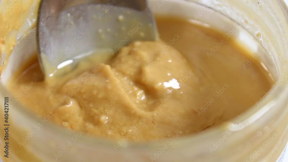 Stir with a spoonful of peanut butter in a jar. Healthy food. Close-up, selective shot. Stir with a spoonful of peanut butter in a jar. Healthy food. Close-up, selective shot.