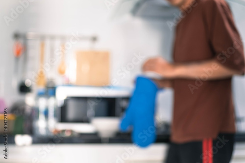 Blurred man asian cooking in kitchen of home He holds bowl and spatula to great hand on microwave in kitchen blurred background