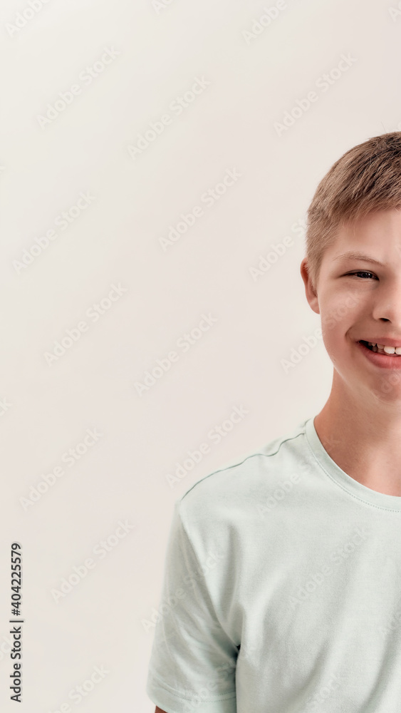 Close up half face portrait of cheerful disabled boy with Down syndrome smiling at camera while posing isolated over white background Close up half face portrait of cheerful disabled boy with Down syndrome smiling at camera while posing isolated over white background