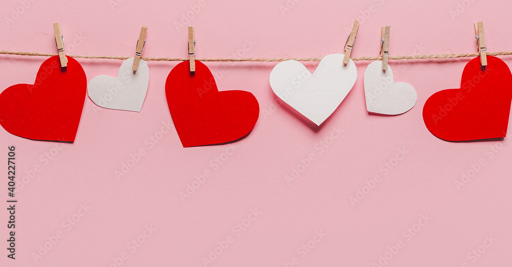 white and red heart pin on a rope on isolated pink background, love and valentine concept