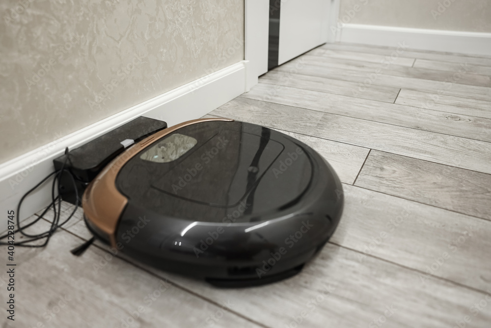 A modern robot vacuum cleaner stands at a charging station, top view. New technologies A modern robot vacuum cleaner stands at a charging station, top view. New technologies