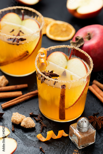 Hard apple cider spiced cocktail with sliced red apples, cinnamon, cardamom and star anise