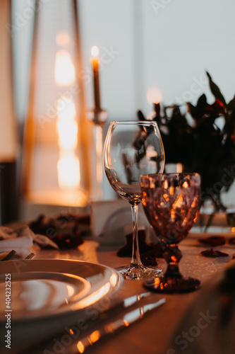 Luxury romantic candlelight dinner for couple. Table setup with candles and rose petals at night. Valentine decoration
