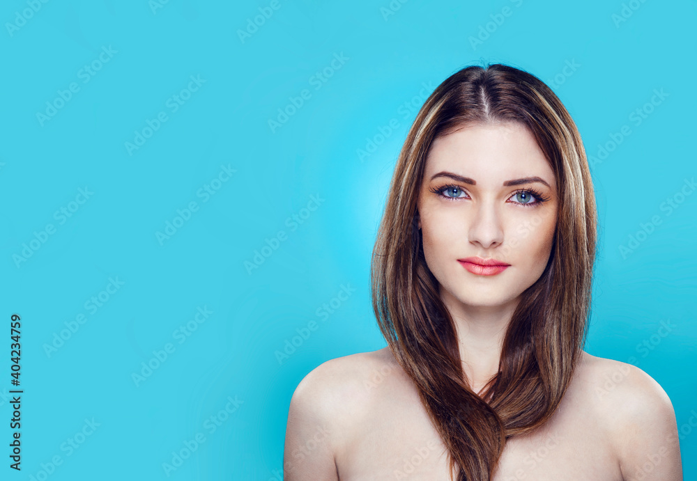 Front closeup portrait of a female model with bare shoulders with makeup, over blue background. Space for text.